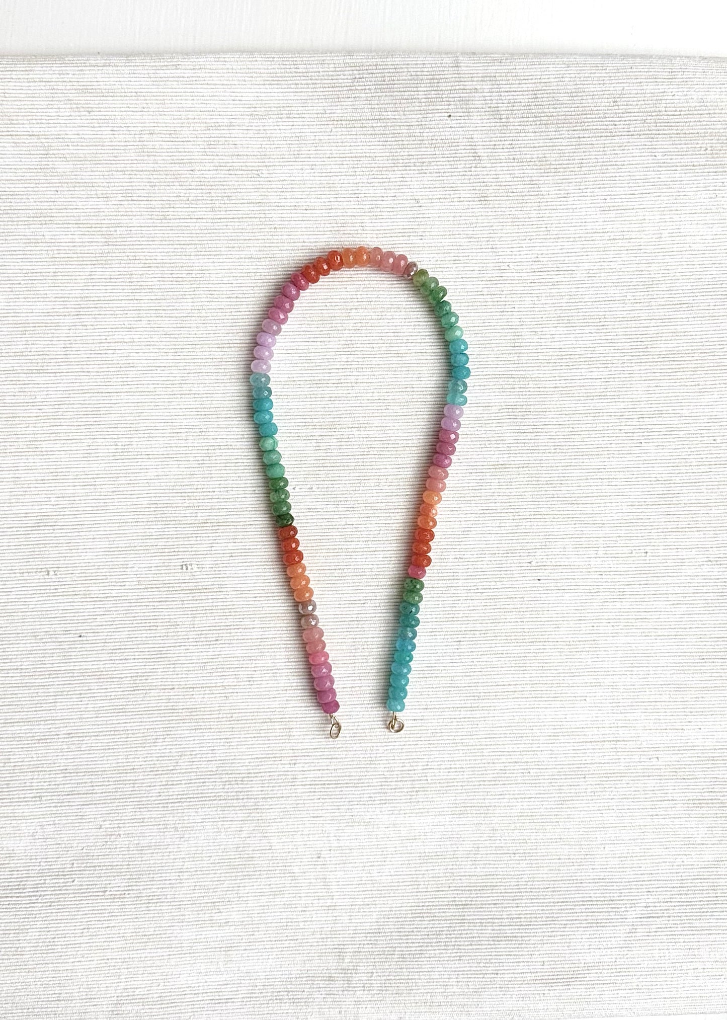 Multicolored beaded necklace on a white textured surface
