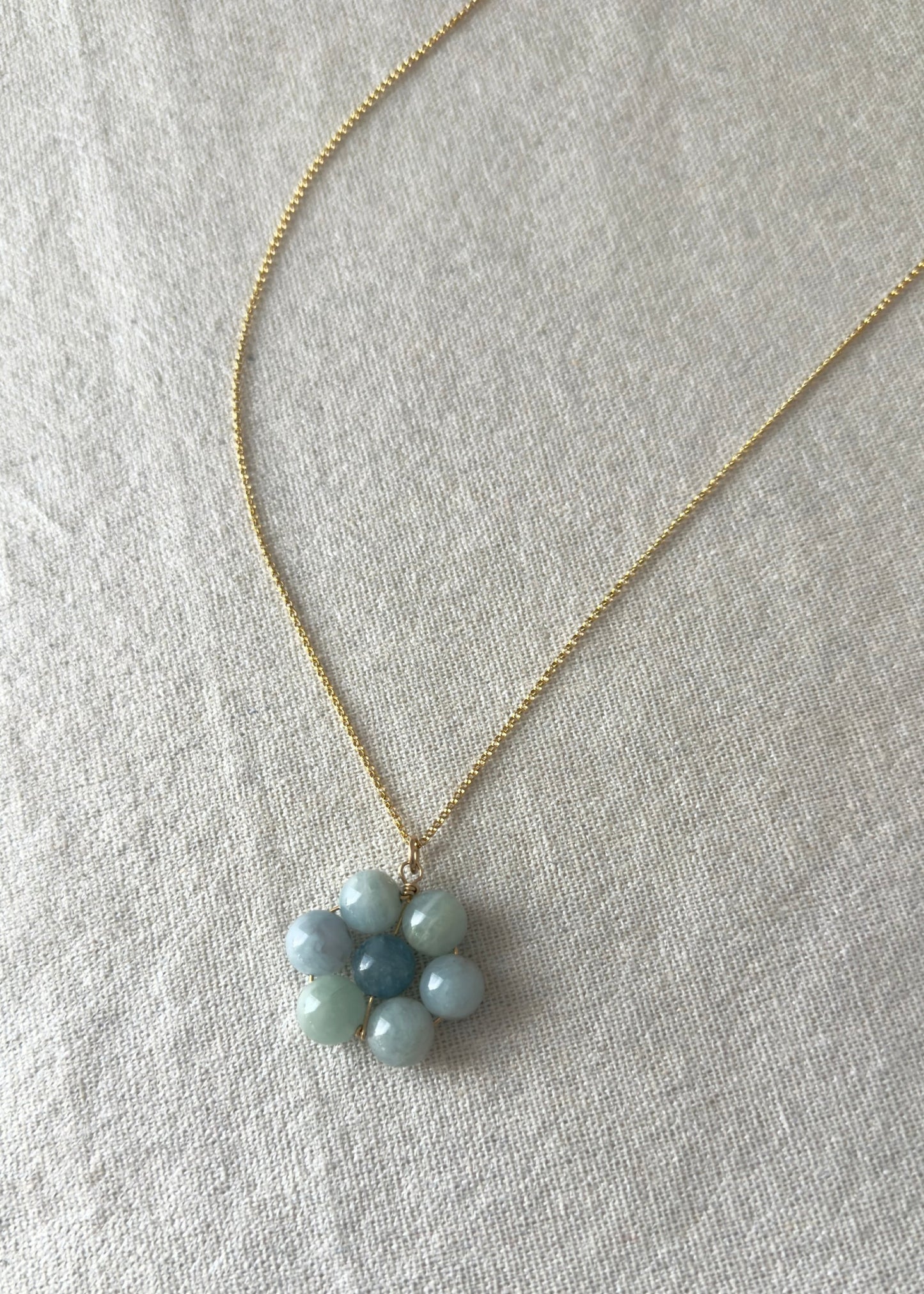 Necklace with a flower-shaped pendant made of small blue beads on a light gray background