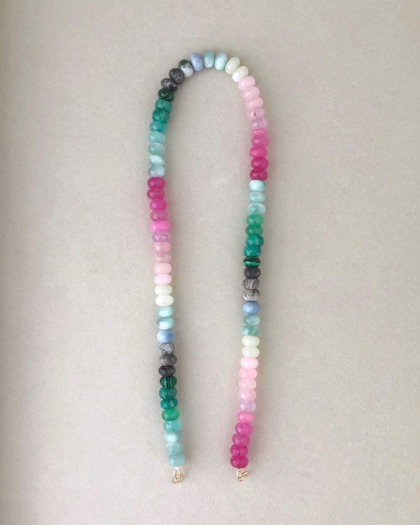 Bright multicolored gemstone bead necklace on a light beige background