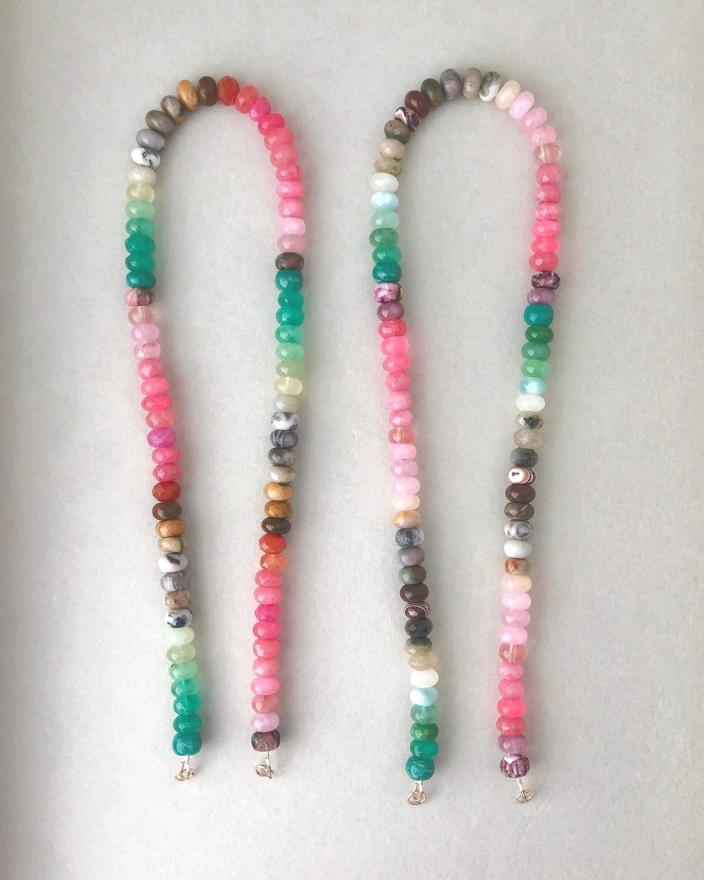 Two beaded gemstone necklaces with colorful mixed ombre effect gemstones on a light gray background