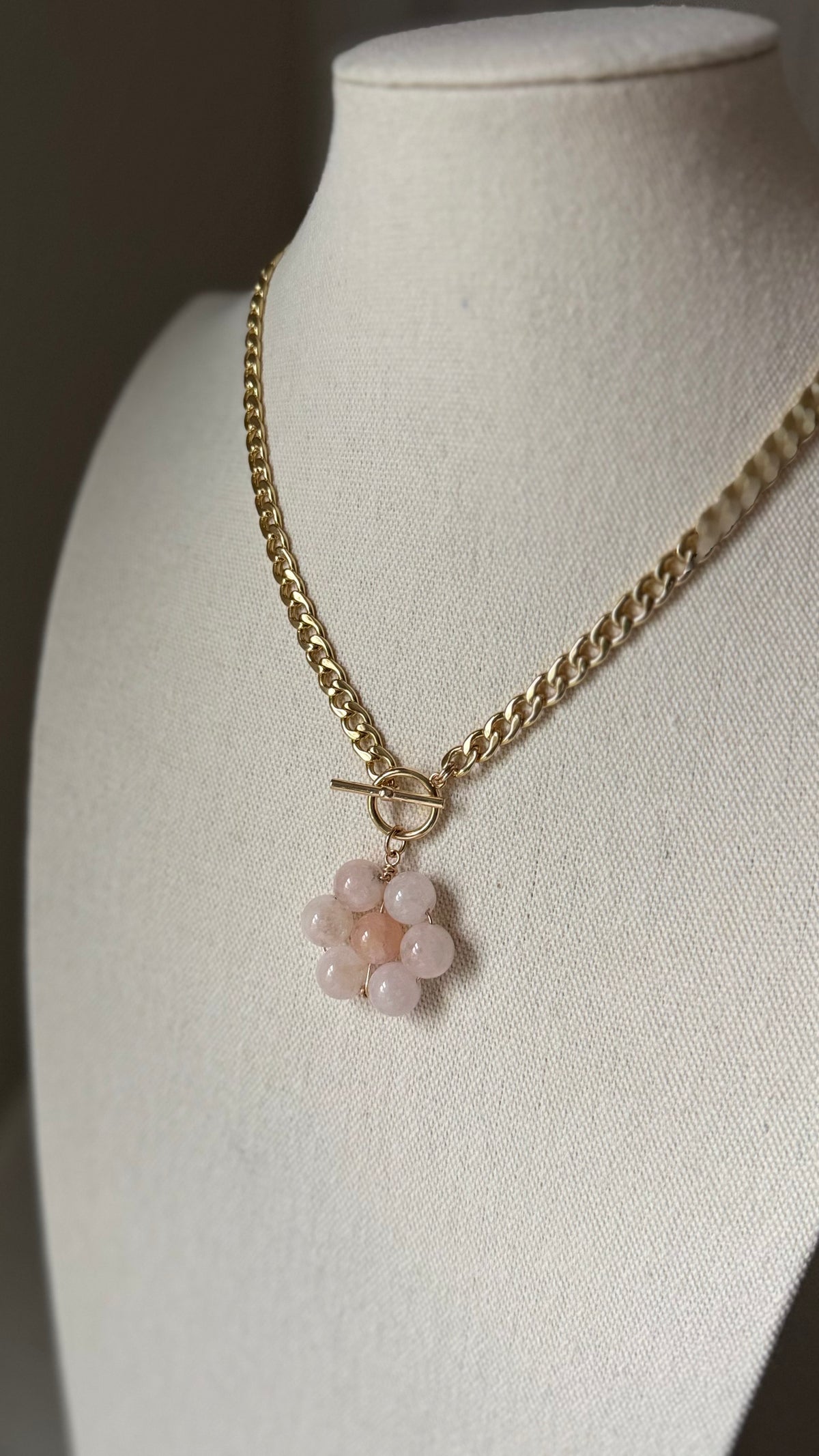 Necklace with a floral pendant on a mannequin bust against a neutral background