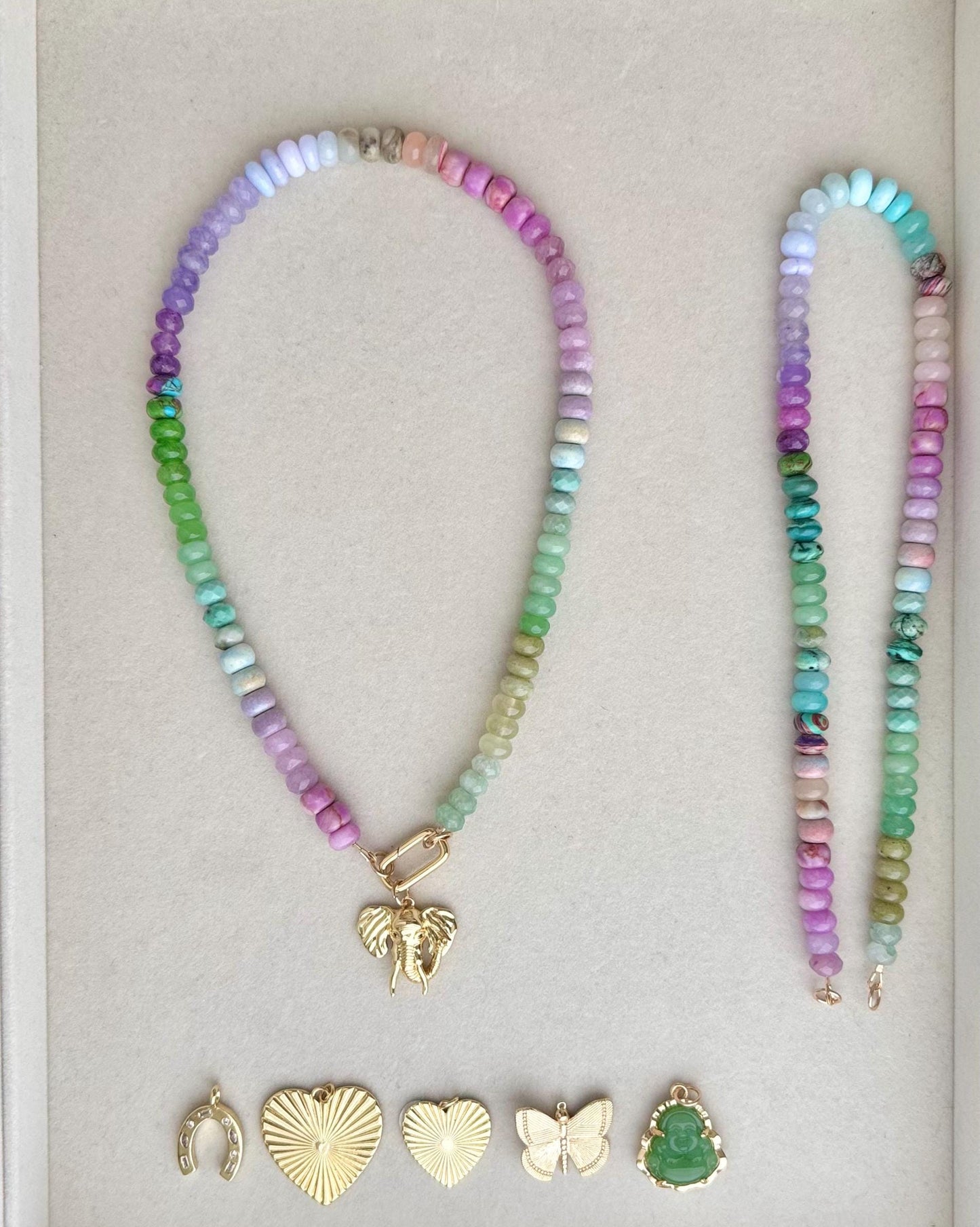 colorful beaded gemstone necklace and coordinating gold charms/pendants and clasp on a neutral background