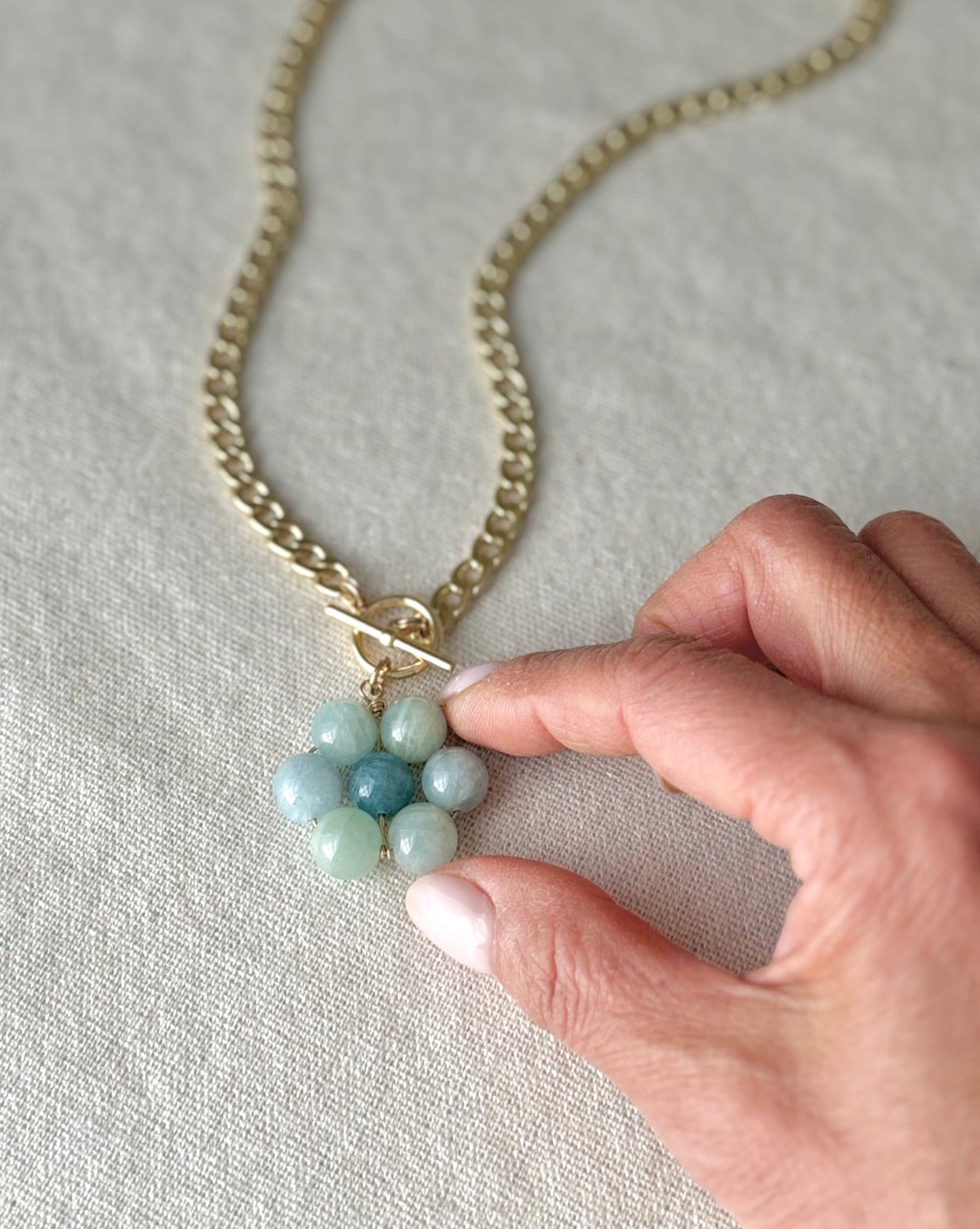 Necklace with turquoise beads held by a hand on a light fabric background