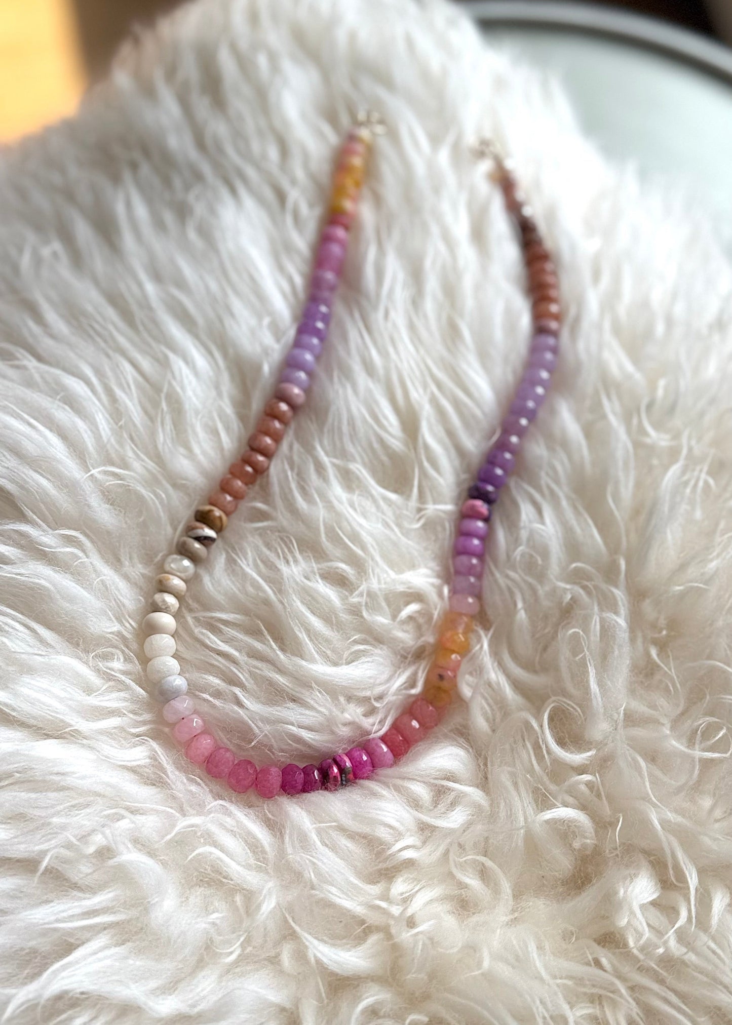Necklace with multicolored beads on a white fluffy surface