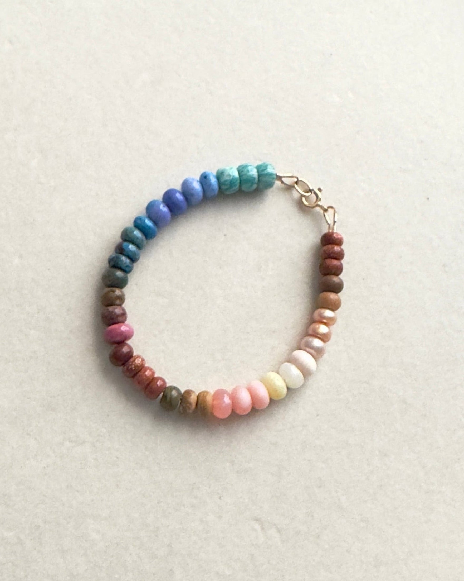 Multicolored ombre effect gemstone beaded bracelet on a light gray surface