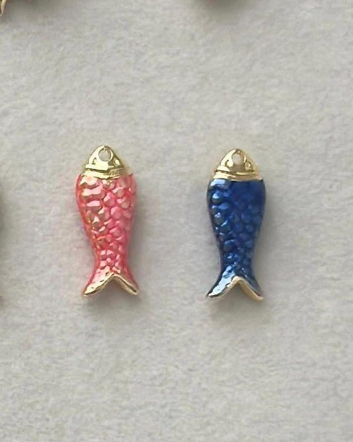 Two fish-shaped charms
, one pink and one blue, on a light gray background.