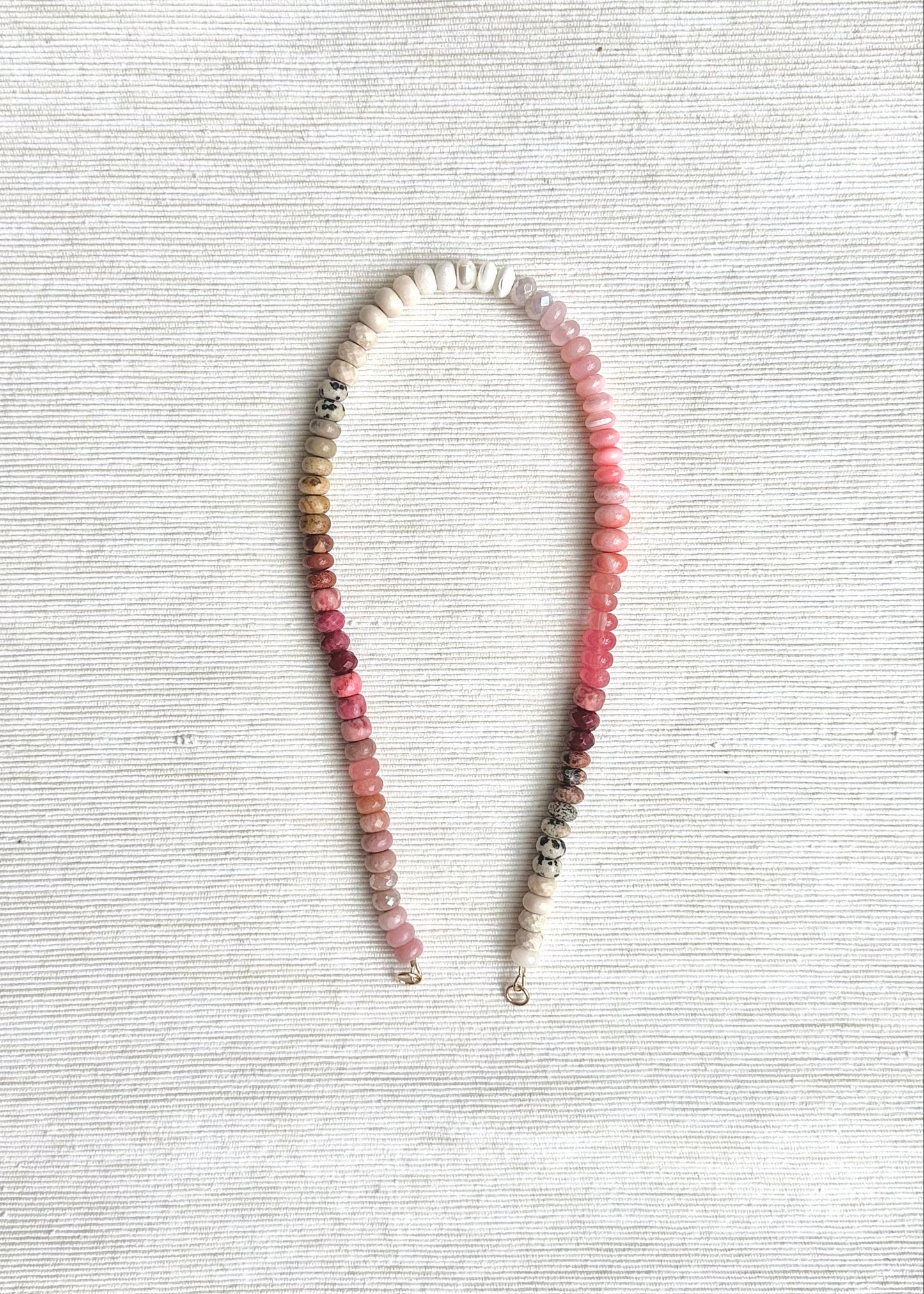 Necklace with pink and white beads on a textured white surface