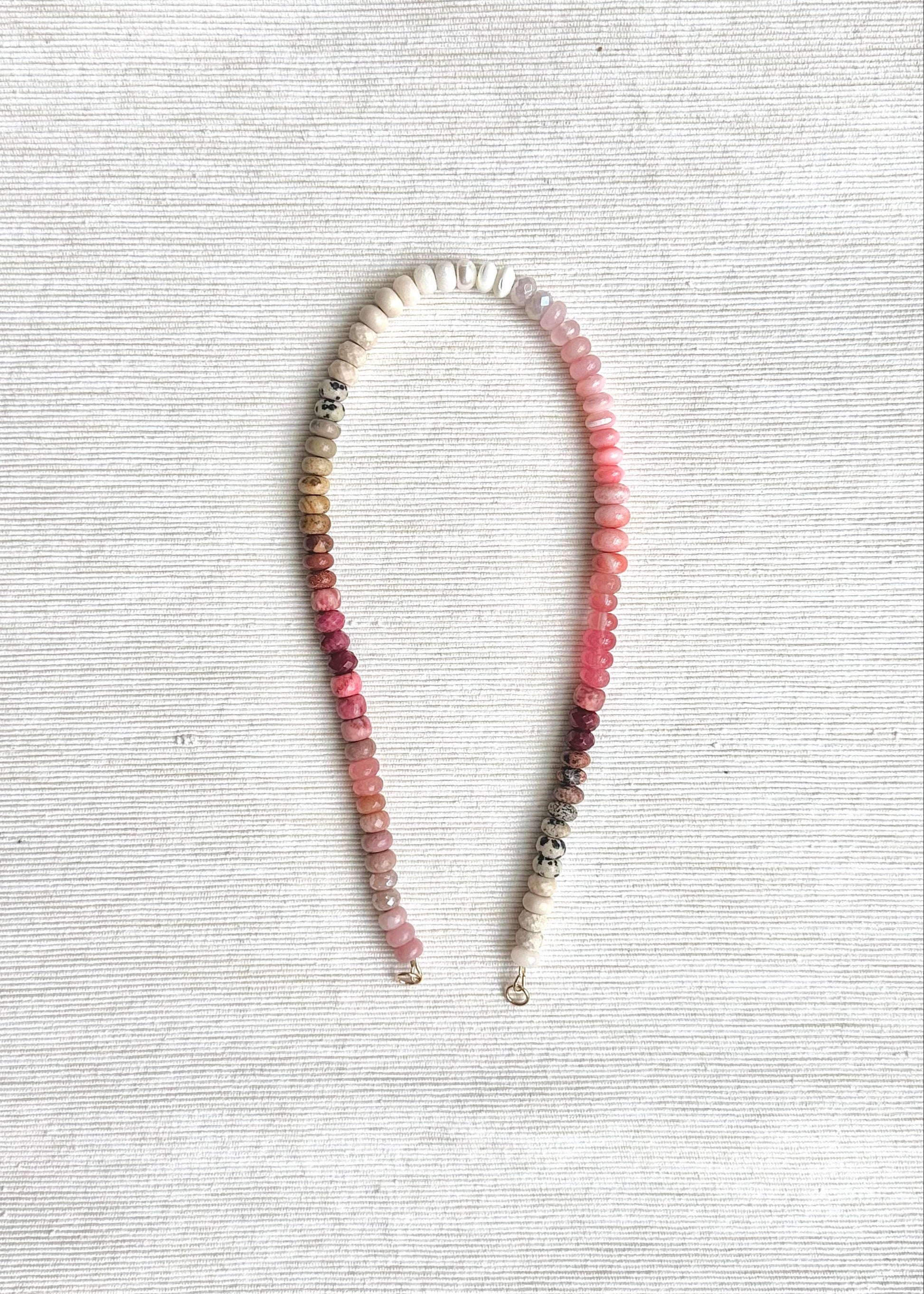 Necklace with pink and white beads on a textured white surface