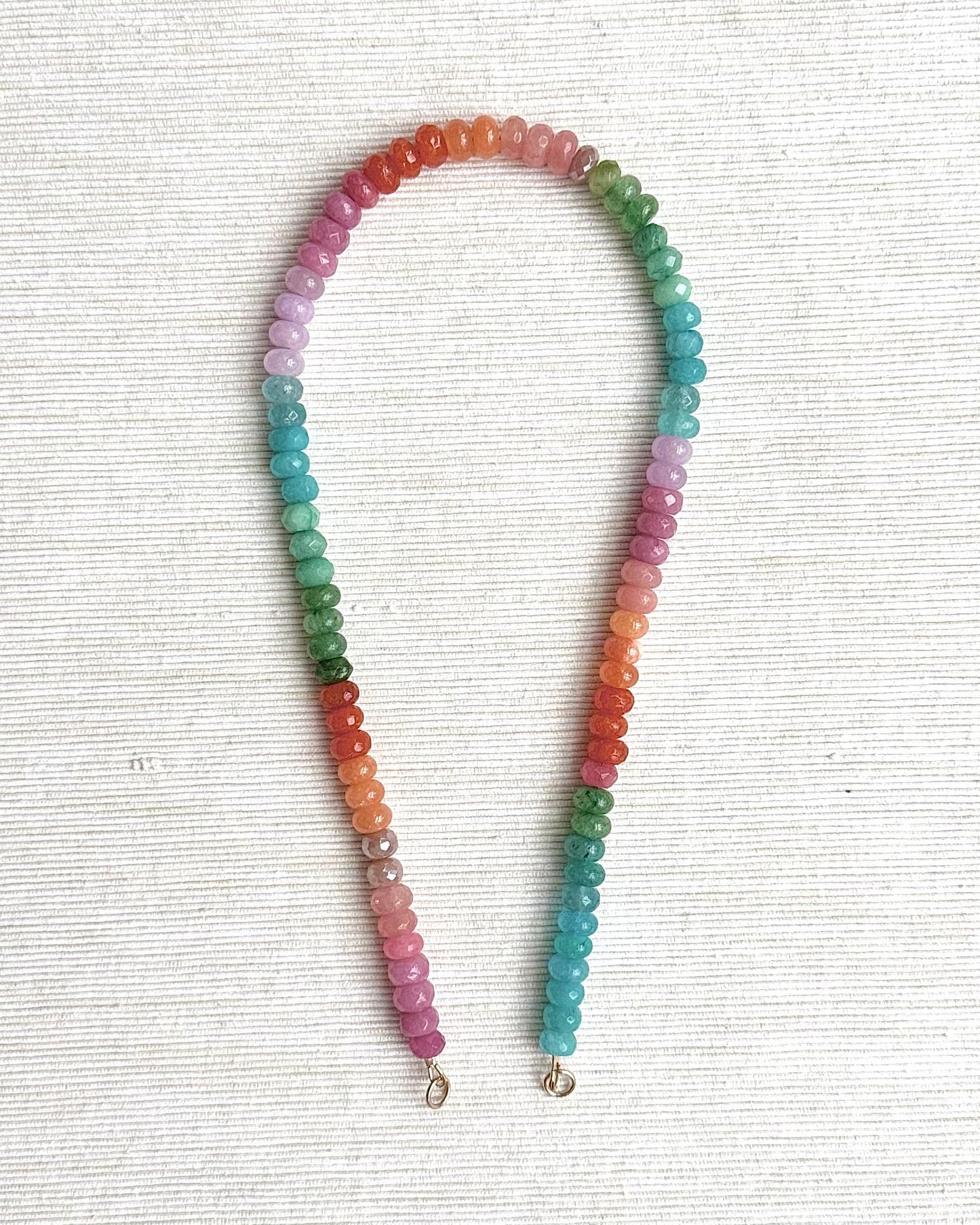 Multicolored beaded necklace on a white textured background