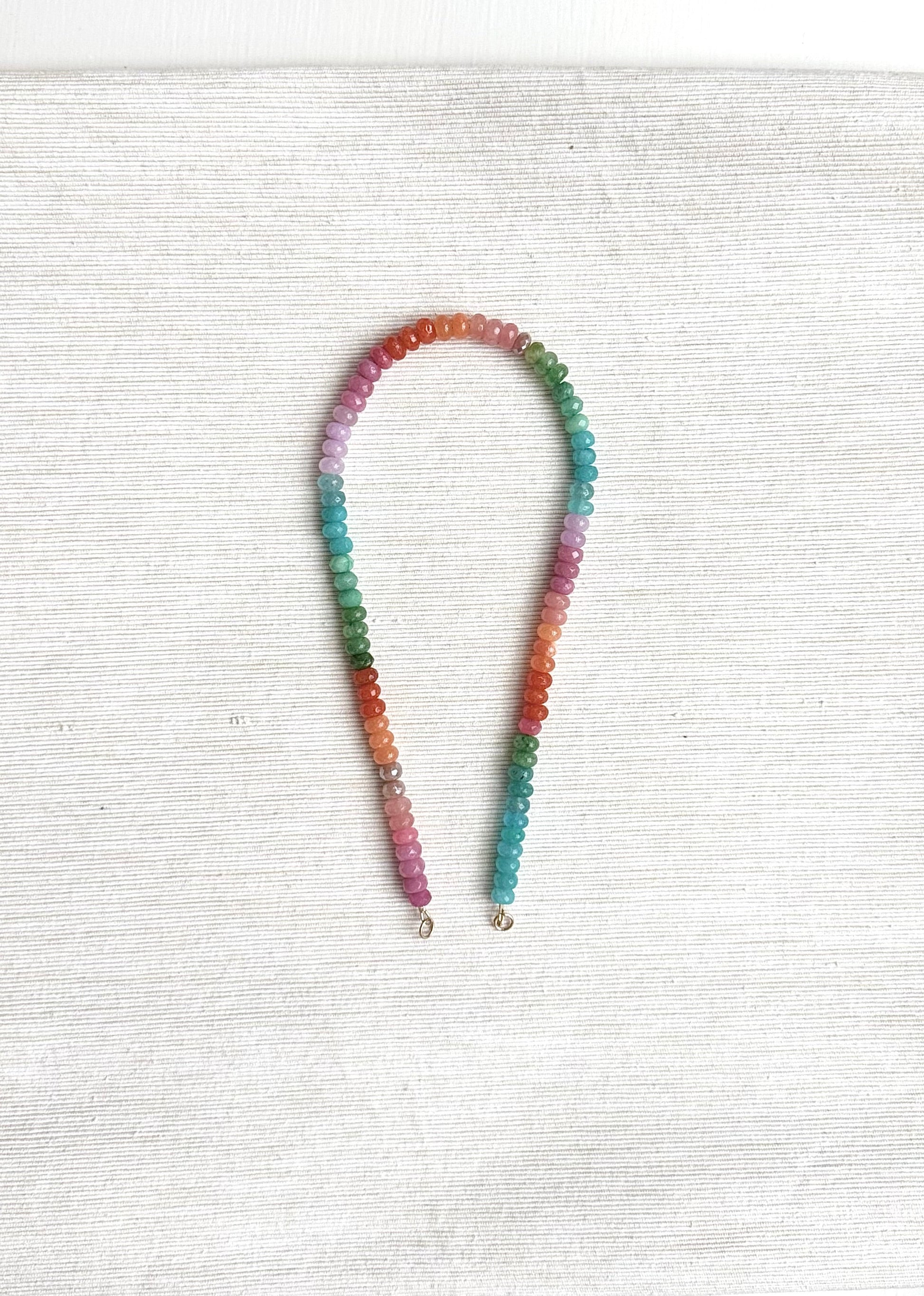 Multicolored beaded necklace on a white textured surface
